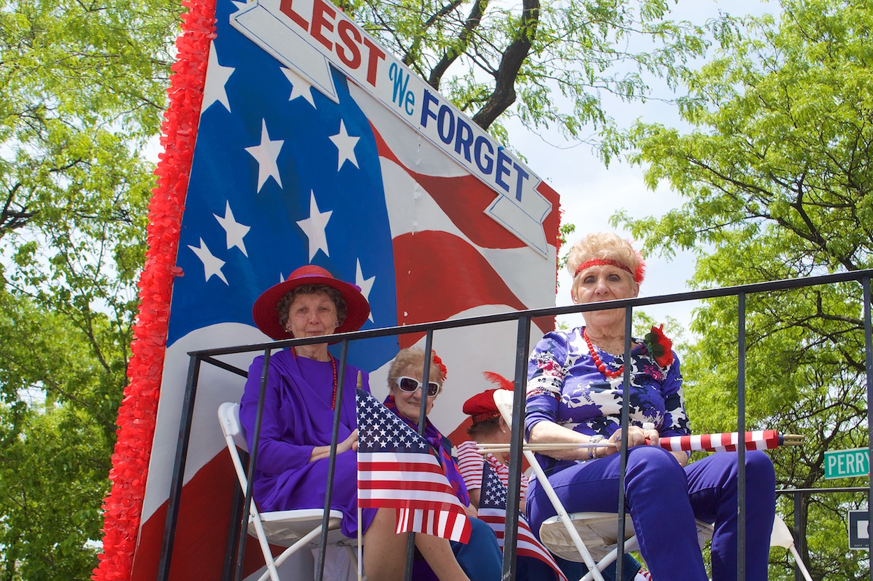 Older women riding in red-white-and blue
                     float in Maspeth Memorial Day parade