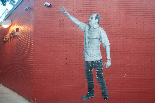 JR street art mural at Sunnyside Library in Queens of man pointing upward from Walking New York series